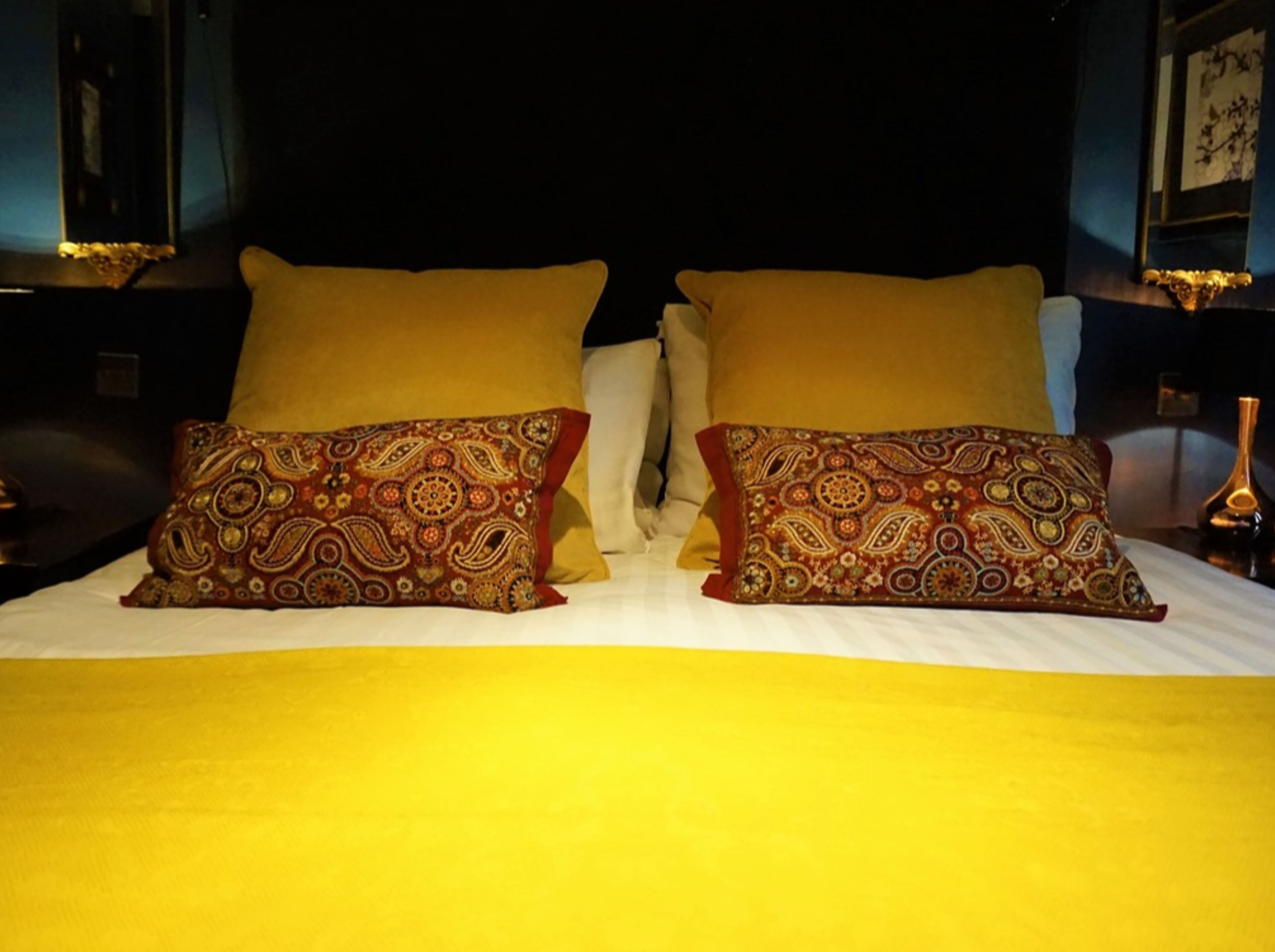 A bed with two pillows, one with a paisley pattern and the other plain.