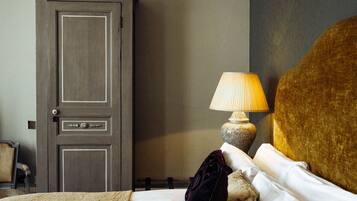 Une chambre d’hôtel comprenant un lit, une table de chevet avec une lampe, une armoire et une chaise.
