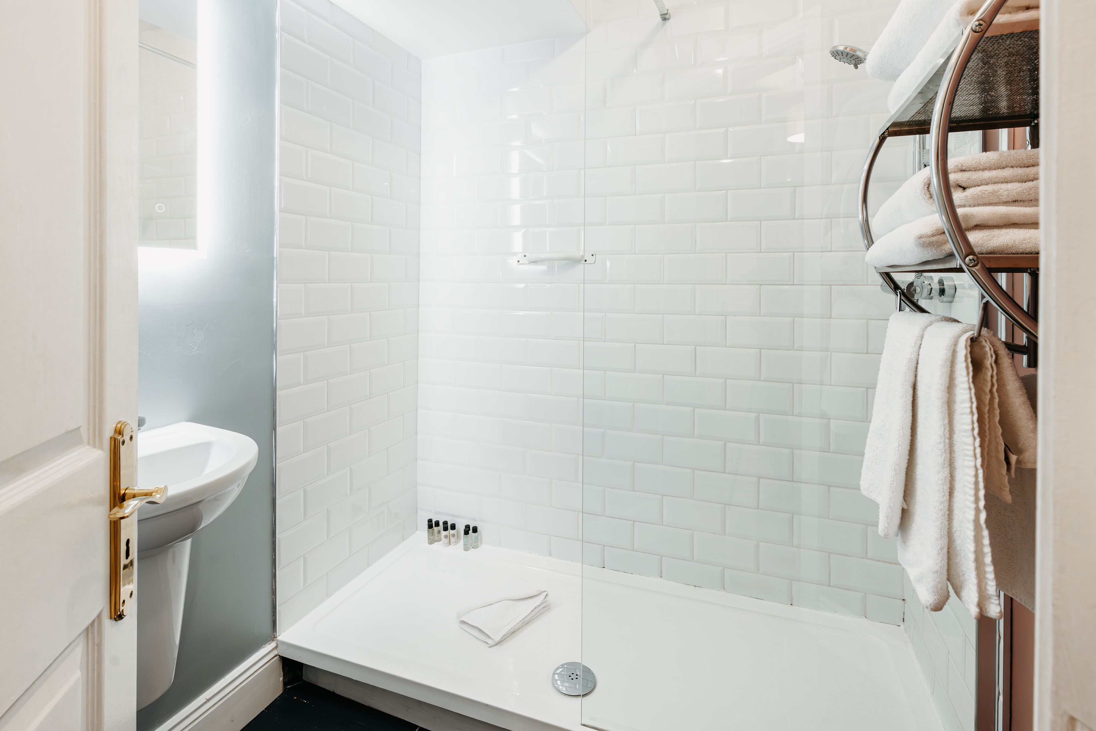 A modern bathroom with a white sink, a glass-enclosed shower, and a towel rack.