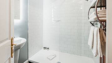 A modern bathroom with a white sink, a glass-enclosed shower, and a towel rack.