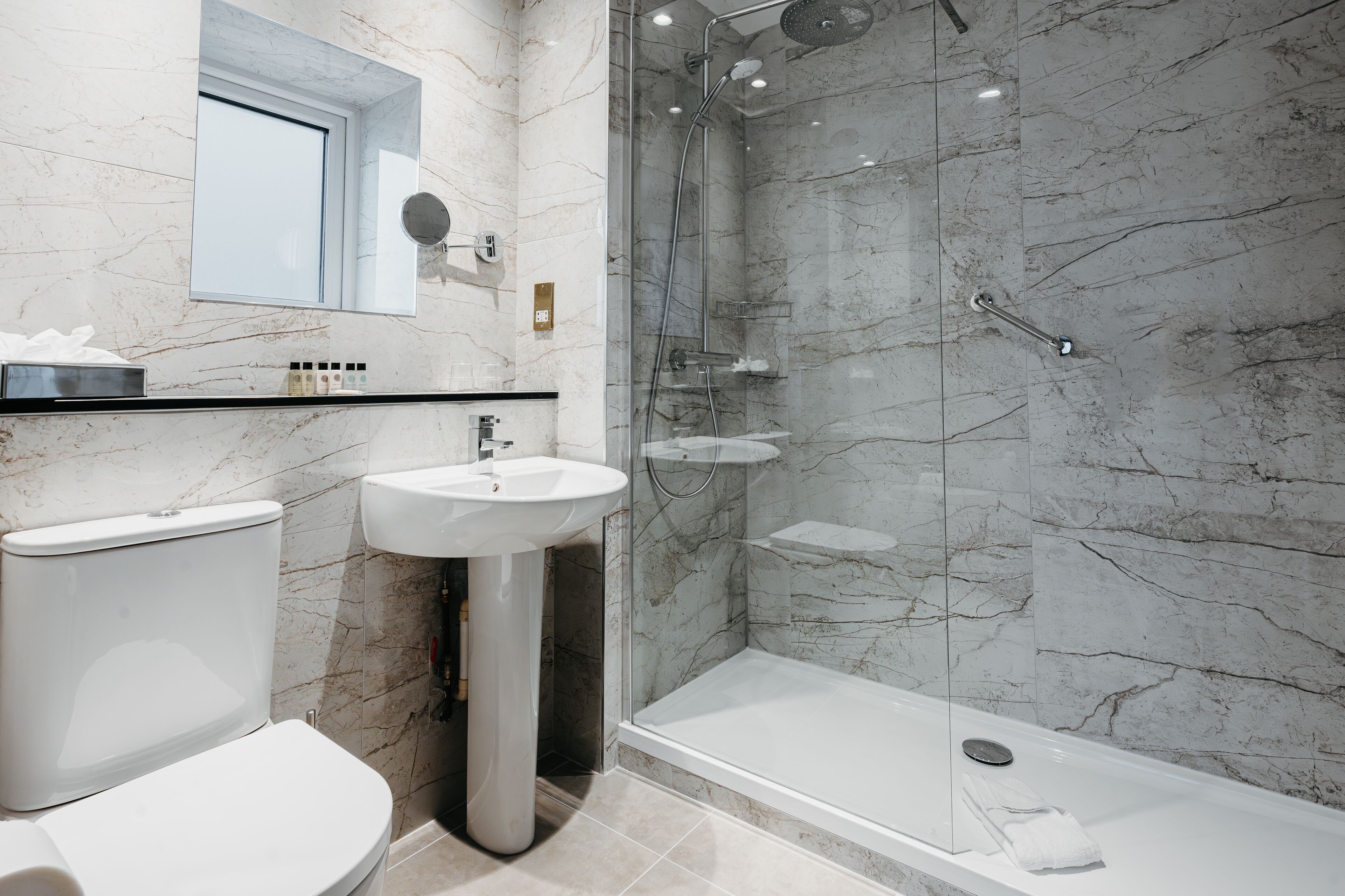 A modern bathroom with a toilet, sink, and glass-enclosed shower.