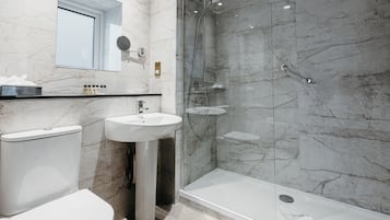 A modern bathroom with a toilet, sink, and glass-enclosed shower.