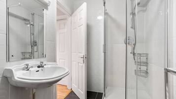 Un baño moderno con ducha envuelta en vidrio, un lavabo blanco y un espejo.
