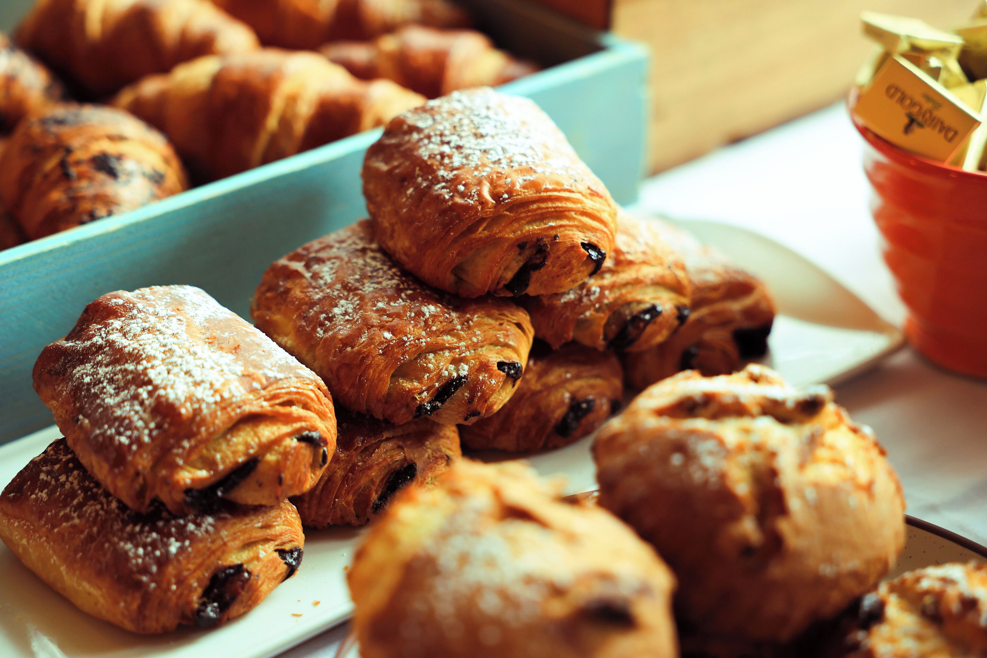 A variety of pastries, including croissants and muffins, arranged on a plate and in a container.
