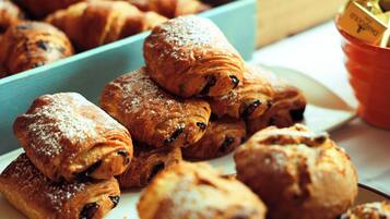 A variety of pastries, including croissants and muffins, arranged on a plate and in a container.