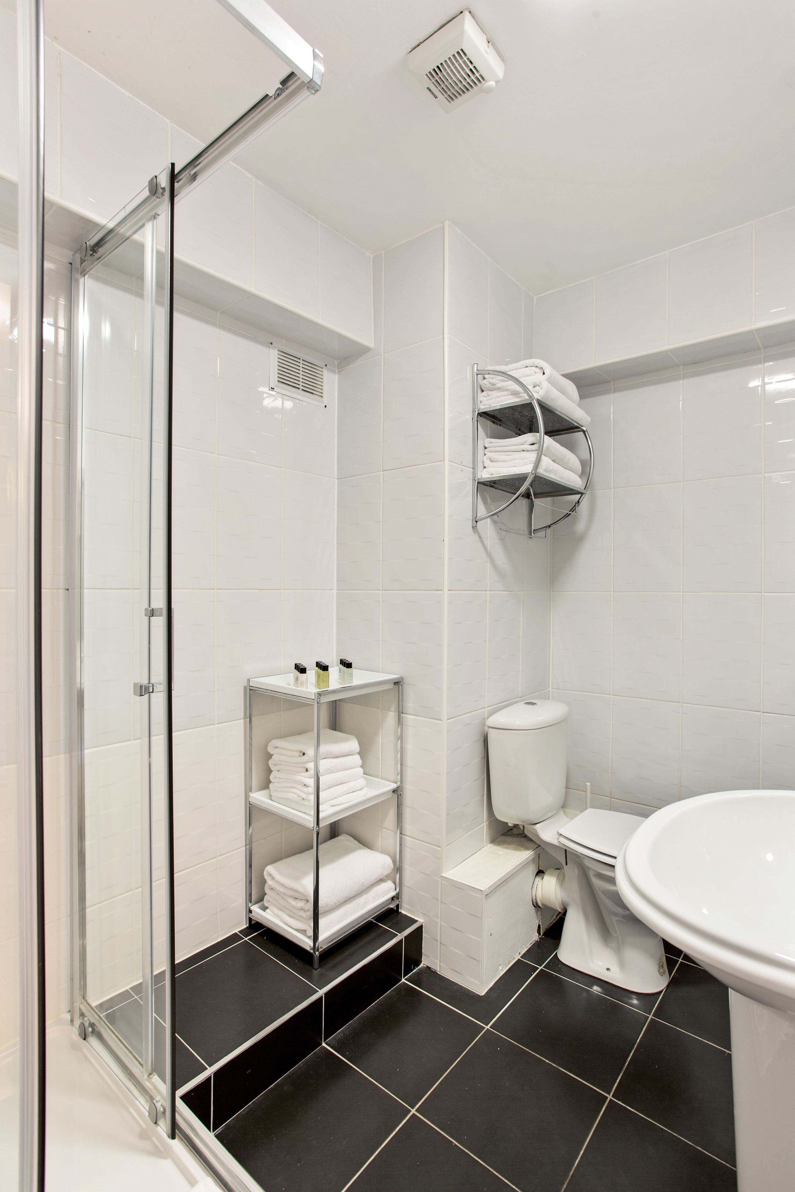 Un baño moderno con cabina de ducha de vidrio, inodoro y lavabo.