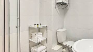 Un baño moderno con cabina de ducha de vidrio, inodoro y lavabo.