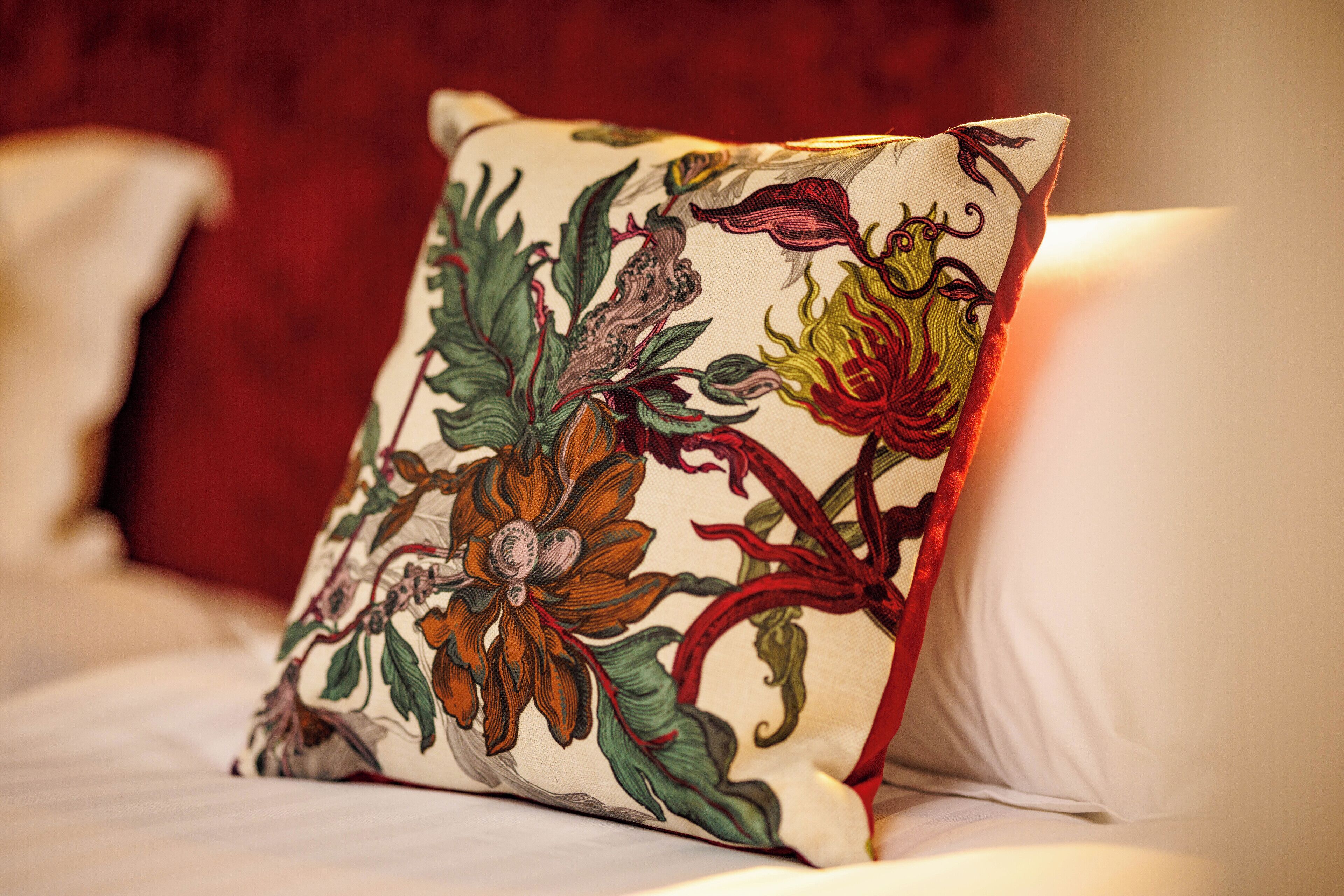 Almofada com padrão floral sobre a cama.