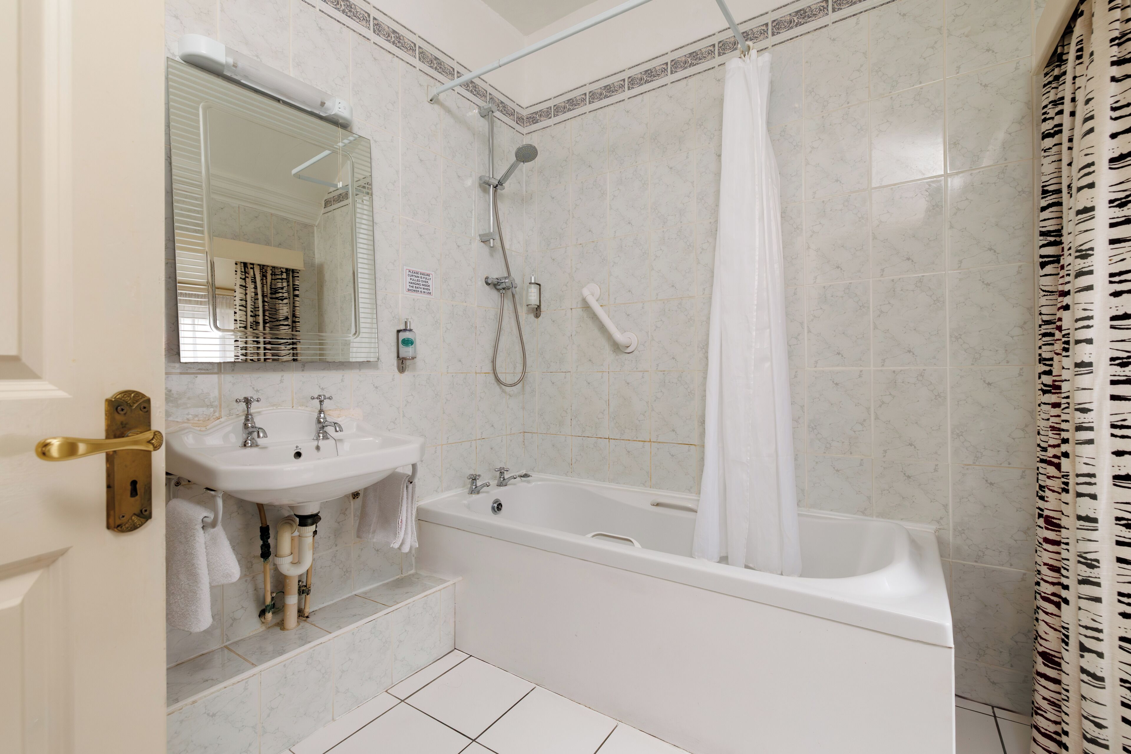 A bathroom with a bathtub, a sink, a mirror, and a shower.