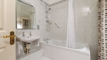 A bathroom with a bathtub, a sink, a mirror, and a shower.