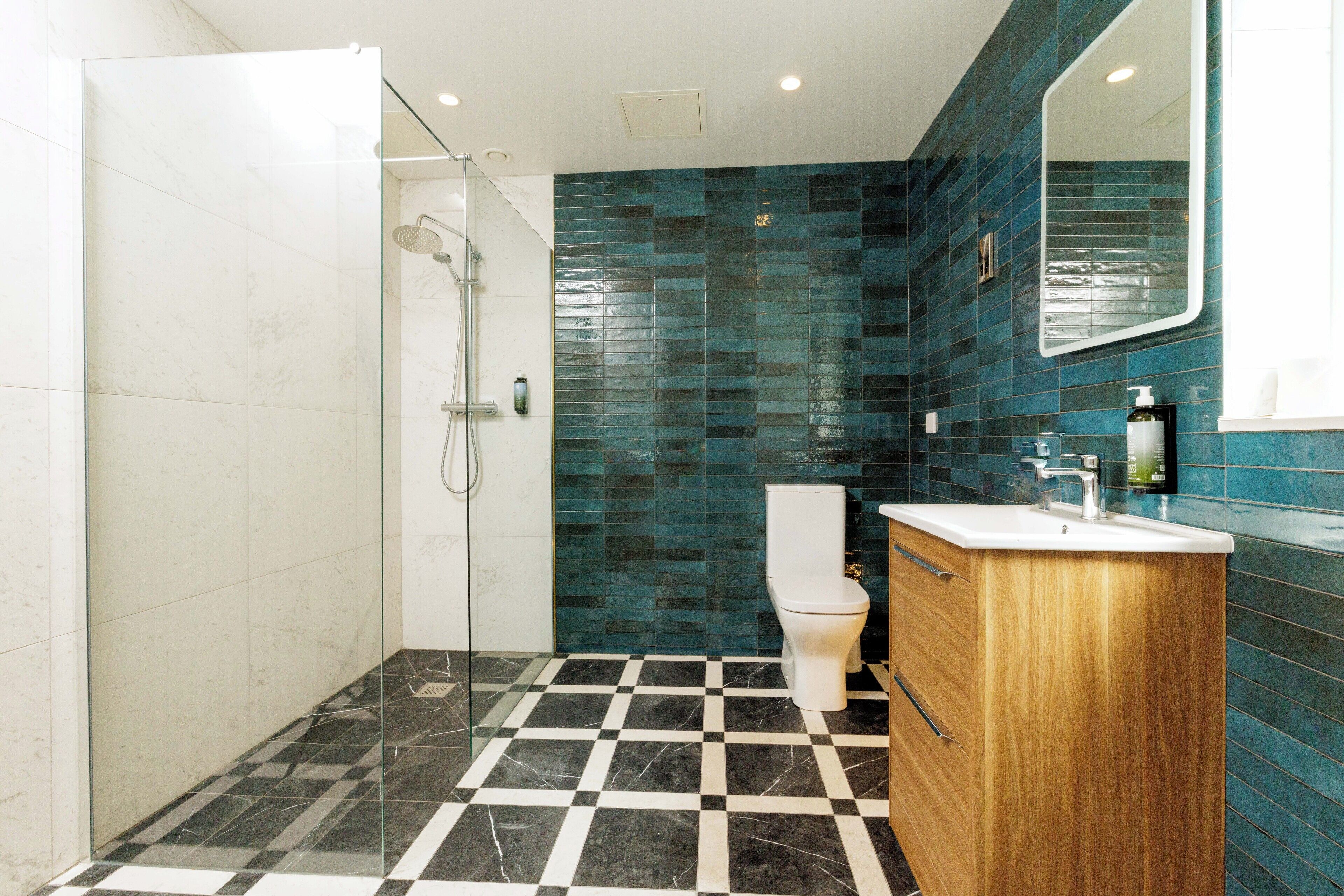 A bathroom with a glass shower enclosure, a toilet, and a sink with a wooden vanity.