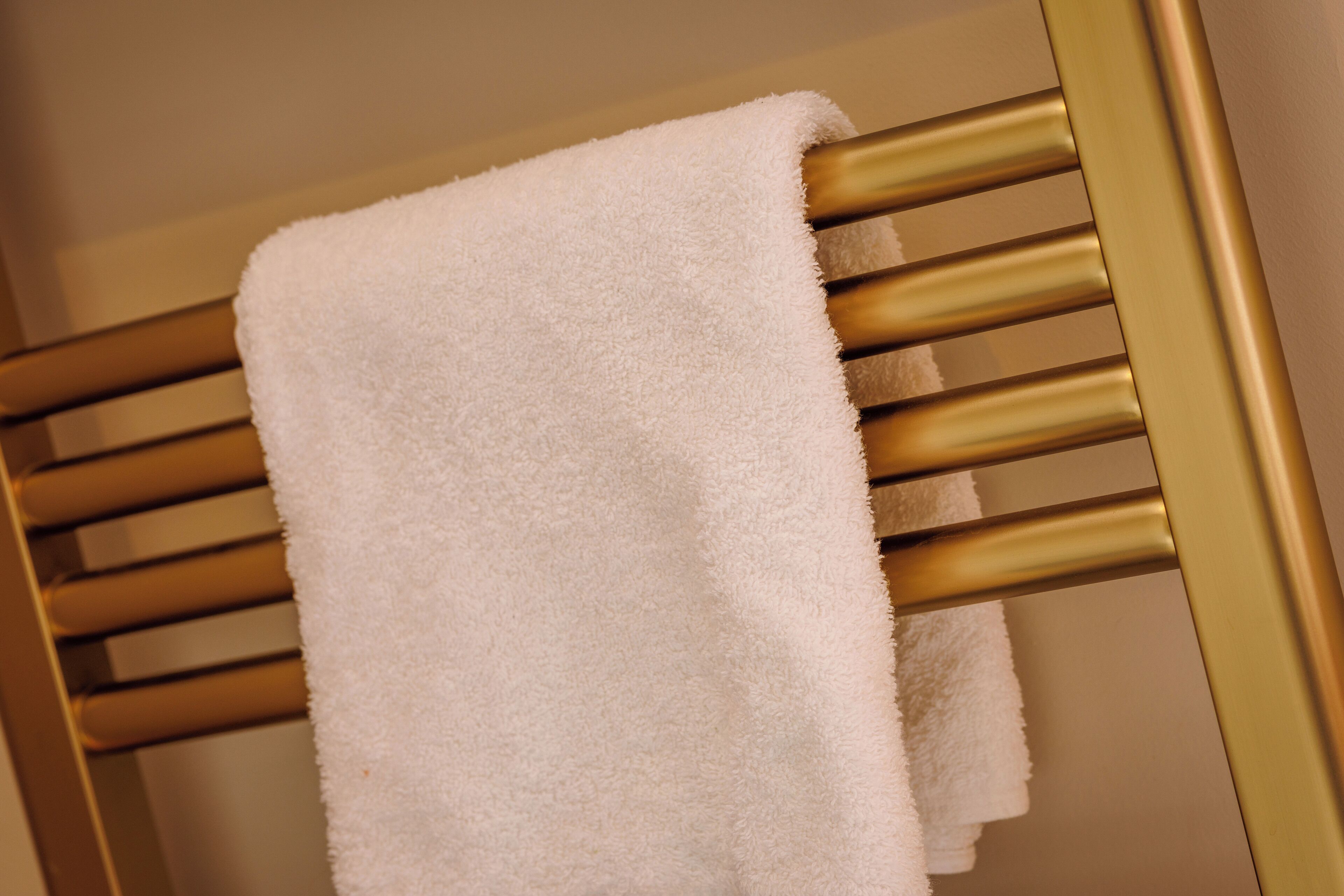A white towel hanging on a gold radiator.