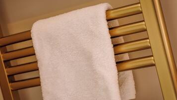 A white towel hanging on a gold radiator.