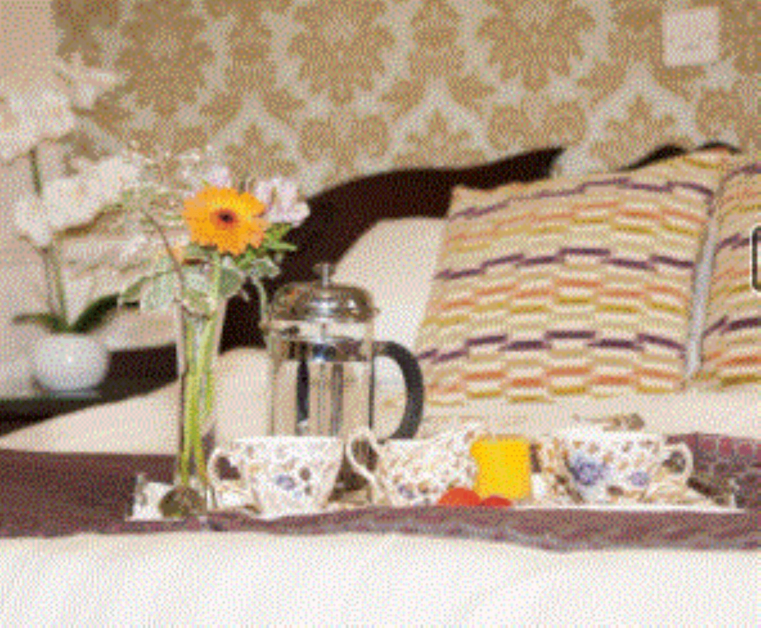 A tray with a teapot, cups, and a vase with flowers on a table.