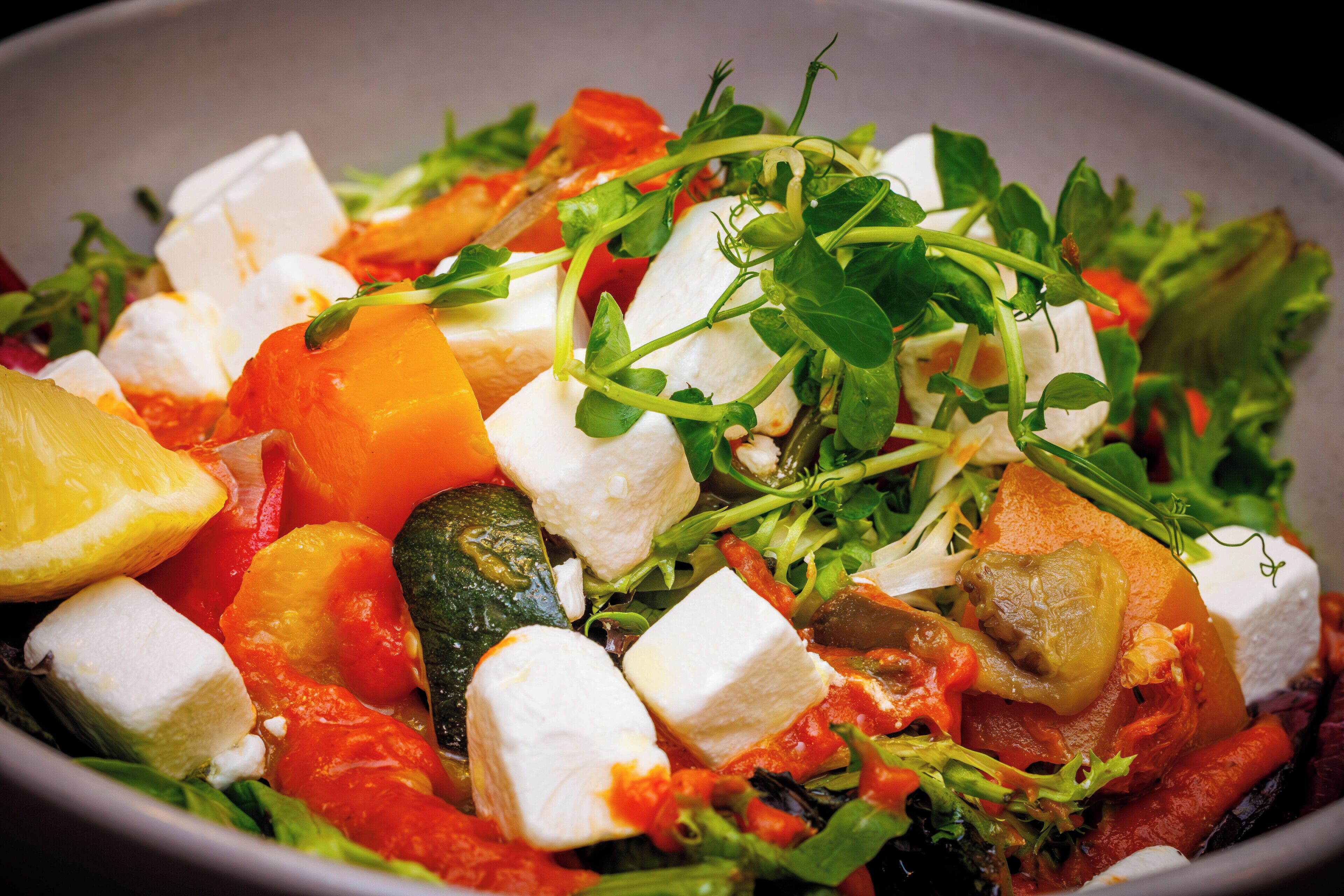 A bowl of salad with various vegetables and cheese.