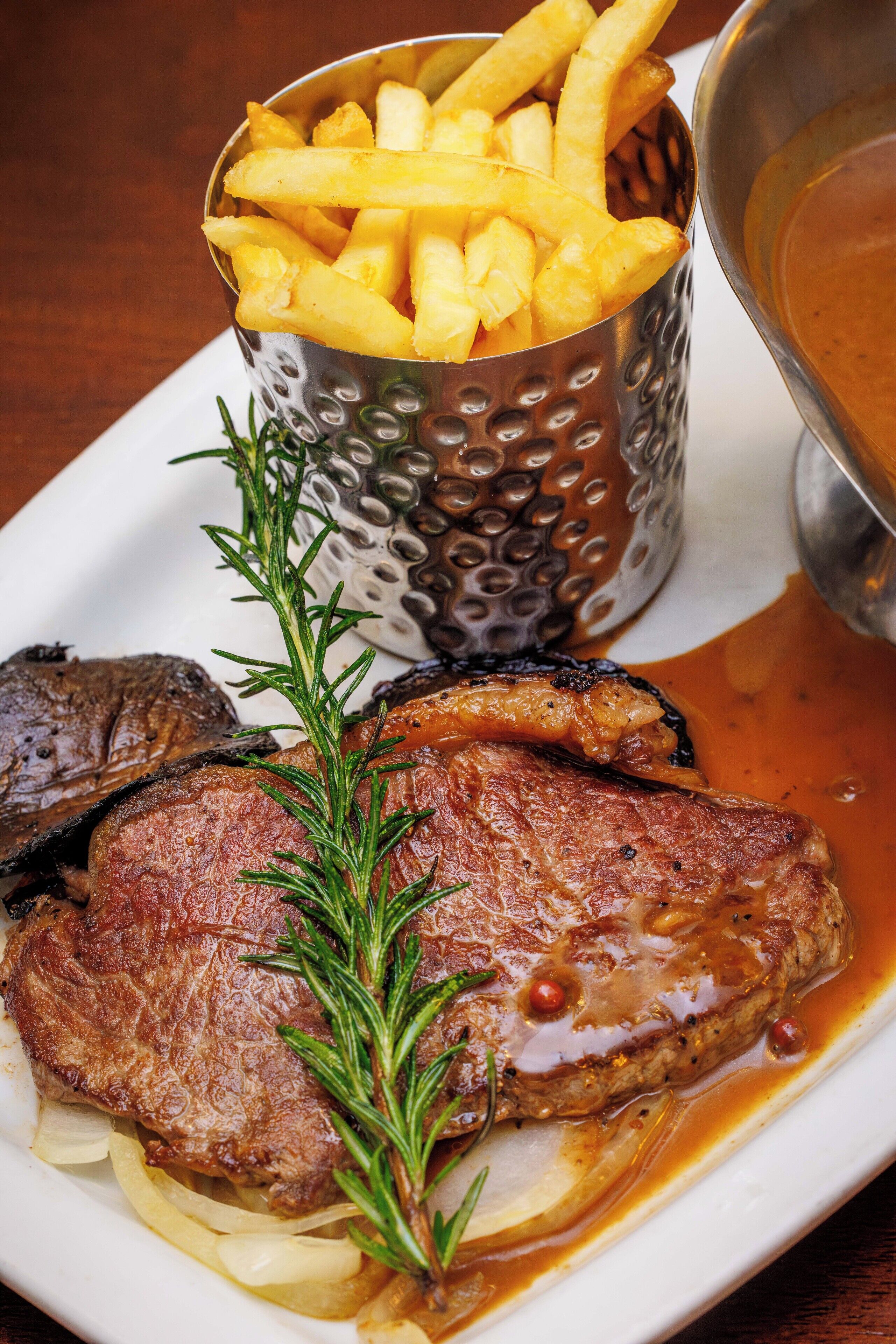 Un plato de carne, papas fritas y salsa.