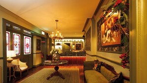 A warmly lit lobby with a round table, a sofa, and a reception desk. - The Club House Hotel (Kilkenny)