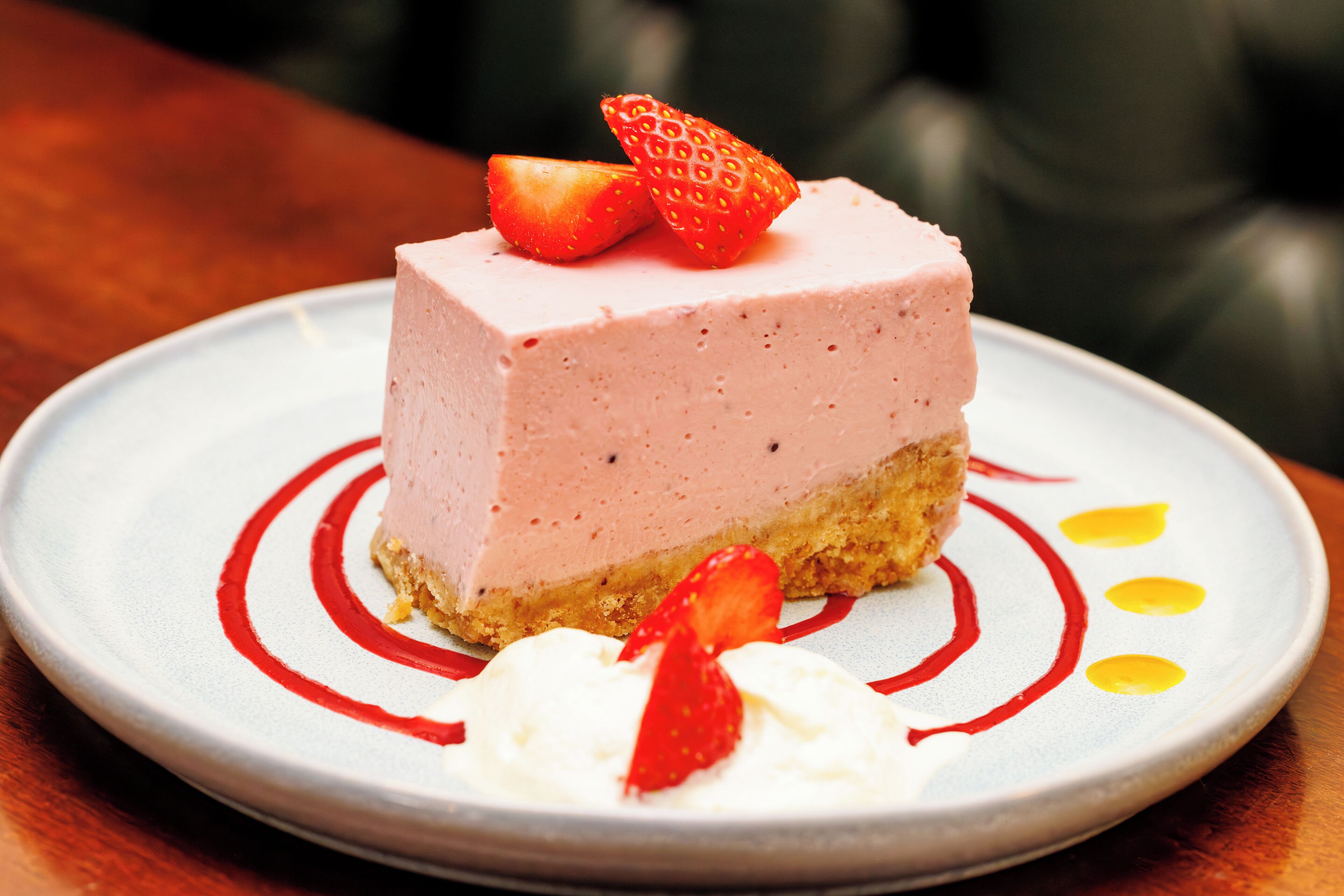 Una porción de pastel de fresa con crema batida y una fresa como decoración.