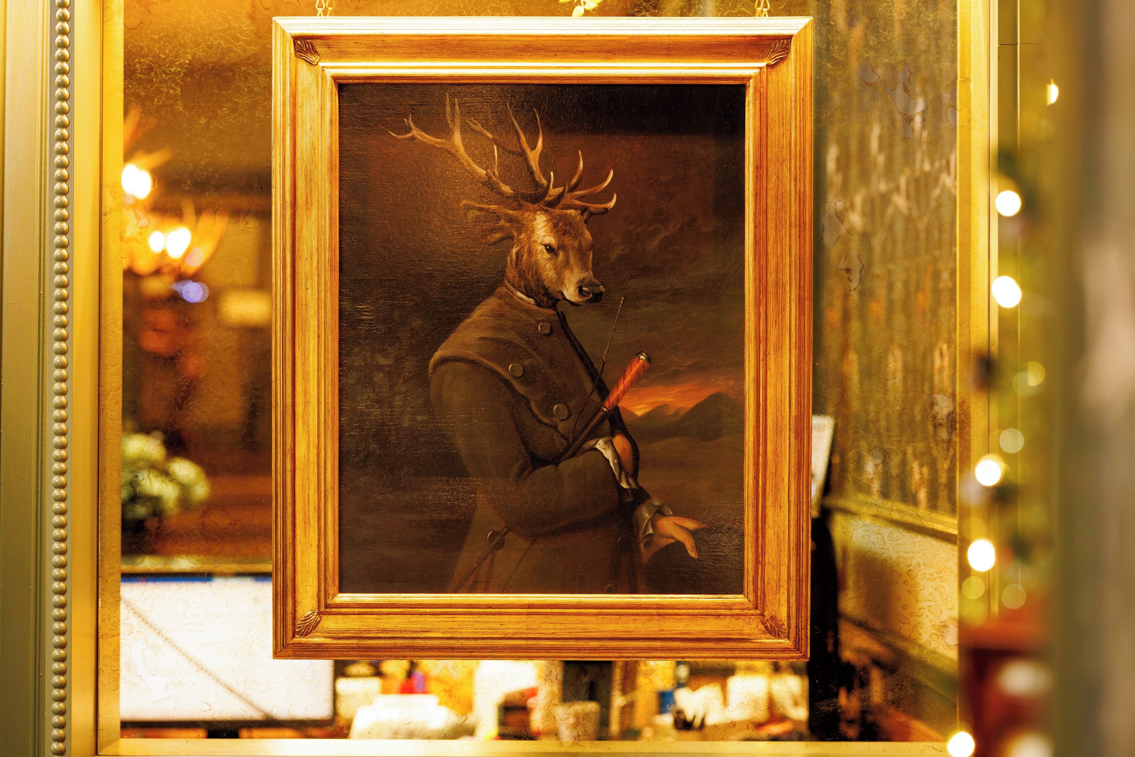 A framed painting of a deer with antlers holding a rifle.