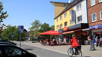 Ett hotell med en gul fasad, ett rött markis och en skylt som visar var man kan parkera.