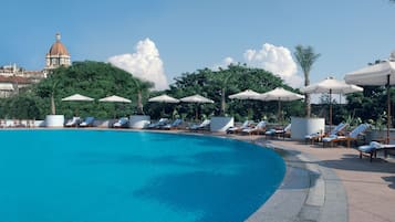 Una piscina al aire libre, sombrillas, tumbonas