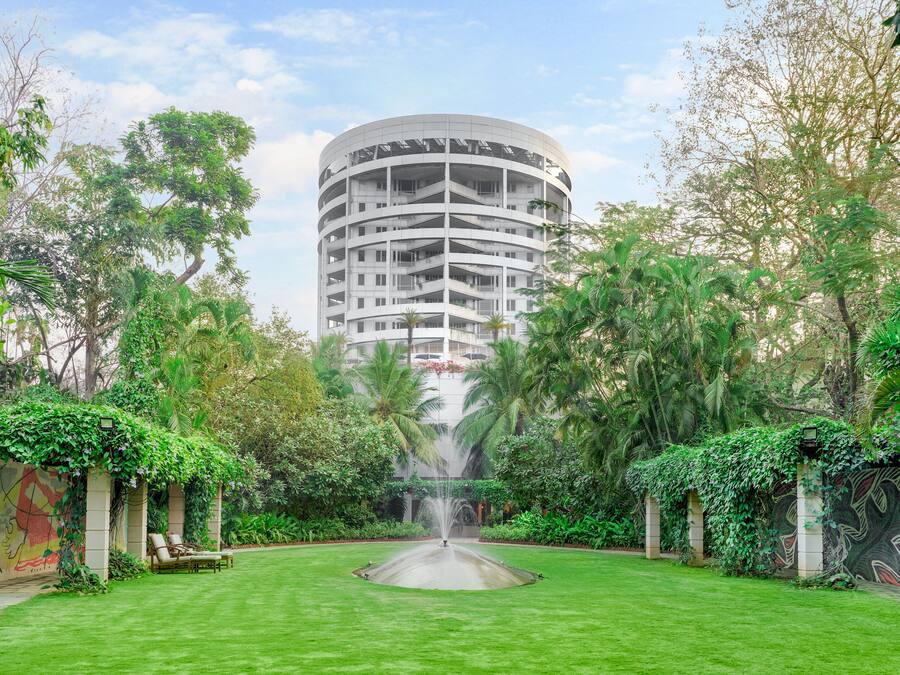 A circular building surrounded by lush greenery and a central fountain.