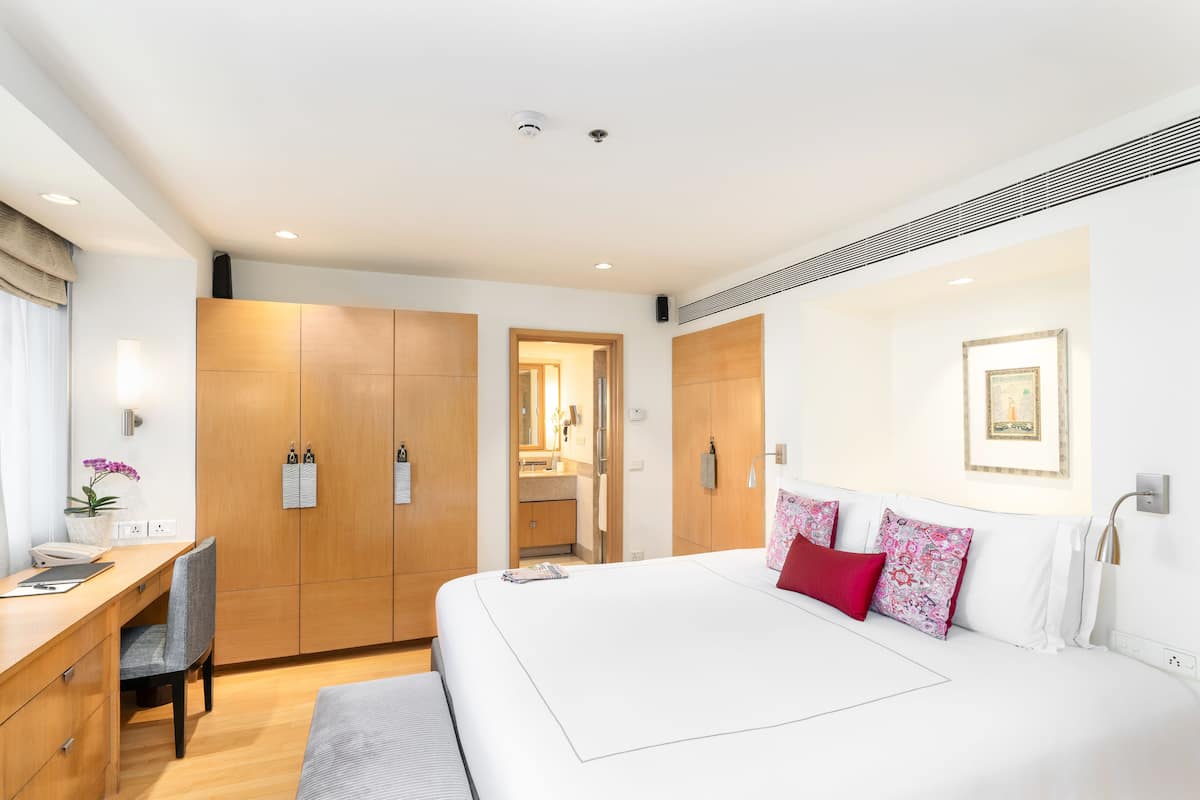Una habitación de hotel moderna con una cama grande, un escritorio y un armario.