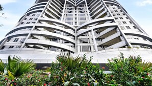 A modern high-rise building with a unique curved architectural design, featuring multiple balconies and a central atrium. - Taj Wellington Mews Luxury Residences (Mumbai)