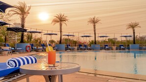 A poolside area with lounge chairs, umbrellas, and a table with a drink. - Taj Wellington Mews Luxury Residences (Mumbai)