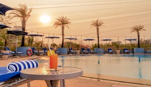 Una piscina al aire libre, sombrillas, sillones reclinables de piscina