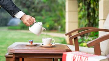 A hand pouring tea into a cup on a wooden table with a book titled "KING" beside it.