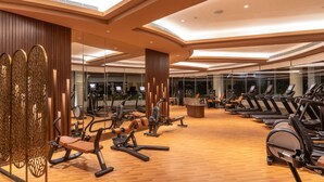 A modern gym with various cardio and strength training equipment, large mirrors, and a wooden floor. - Taj Wellington Mews Luxury Residences (Mumbai)