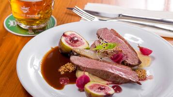 A plate of food with meat, fruit, and sauce, and a glass of beer on a coaster.