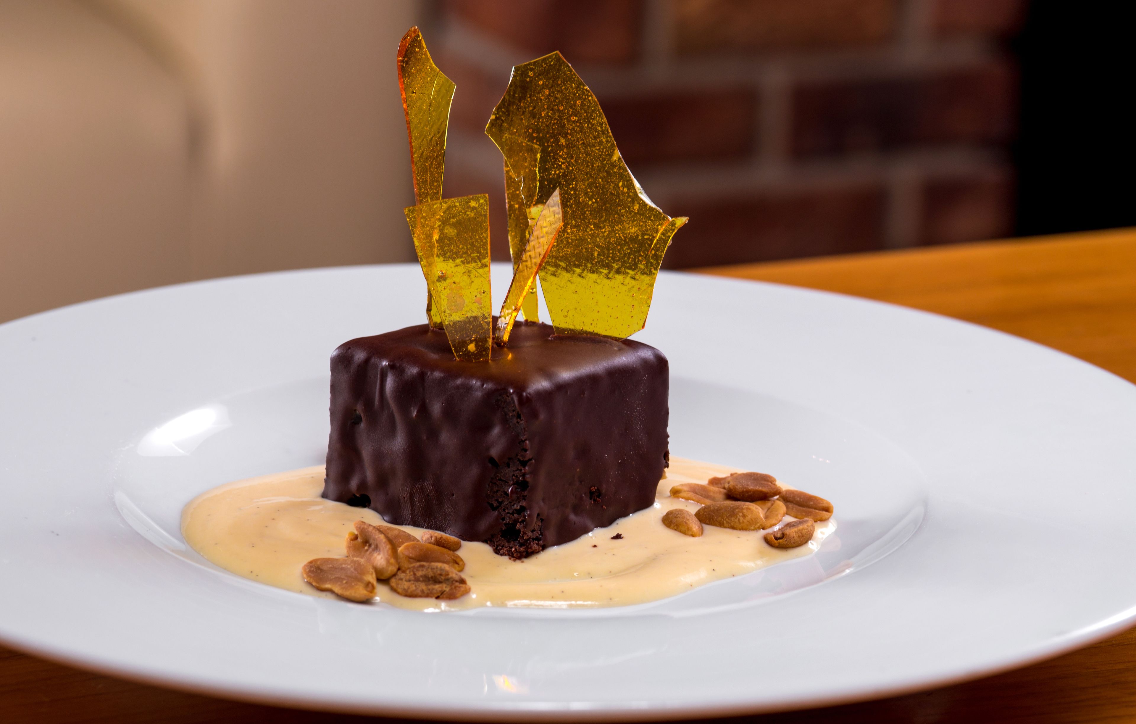 Un dessert servi dans une assiette blanche, accompagné d’une sauce crémeuse et d’amandes.