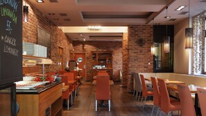 Un restaurante con paredes de ladrillo, mesas de madera y sillas color naranja.