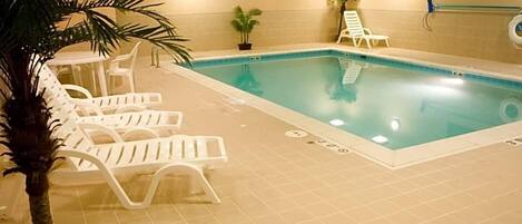 An indoor swimming pool with white lounge chairs and a 'NO DIVING' sign.