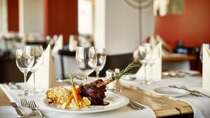 A dining table with a plated meal, wine glasses, and cutlery. - Sorell Hotel Asora (Arosa)
