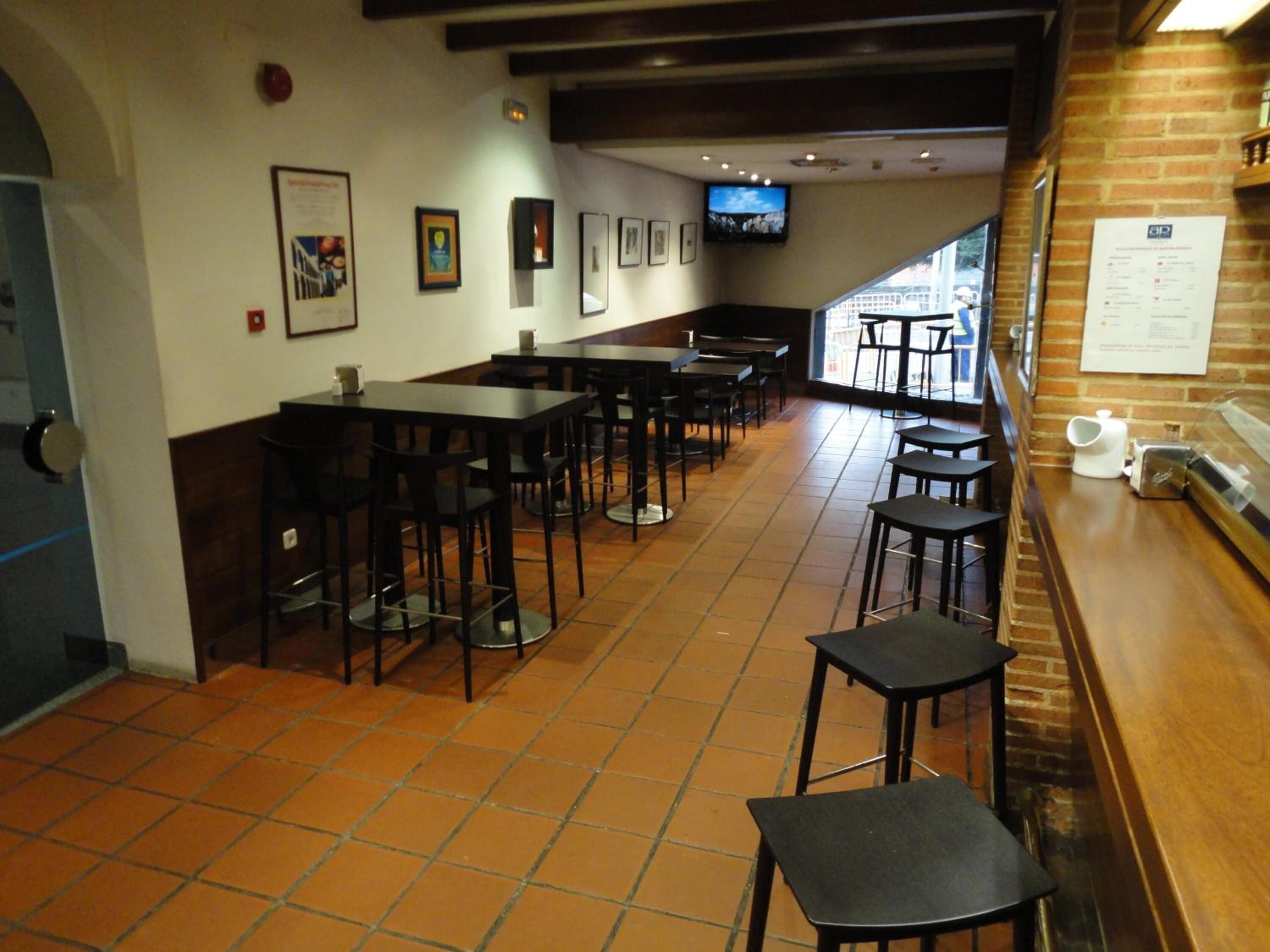 A restaurant with multiple tables and chairs, a tiled floor, and a brick wall.
