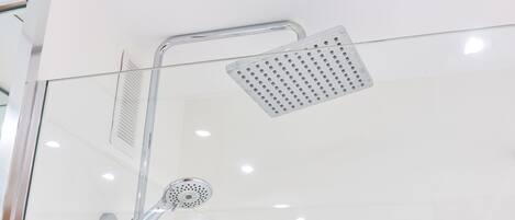 A modern shower with a handheld showerhead and a fixed showerhead with a perforated panel.
