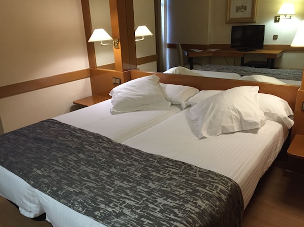 A hotel room with a bed, a nightstand, a desk with a television, and a mirror. - Hotel AR Los Arcos (Segovia)