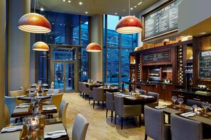 Un restaurant doté d’un bar, de grandes fenêtres et d’un tableau affichant le menu.
