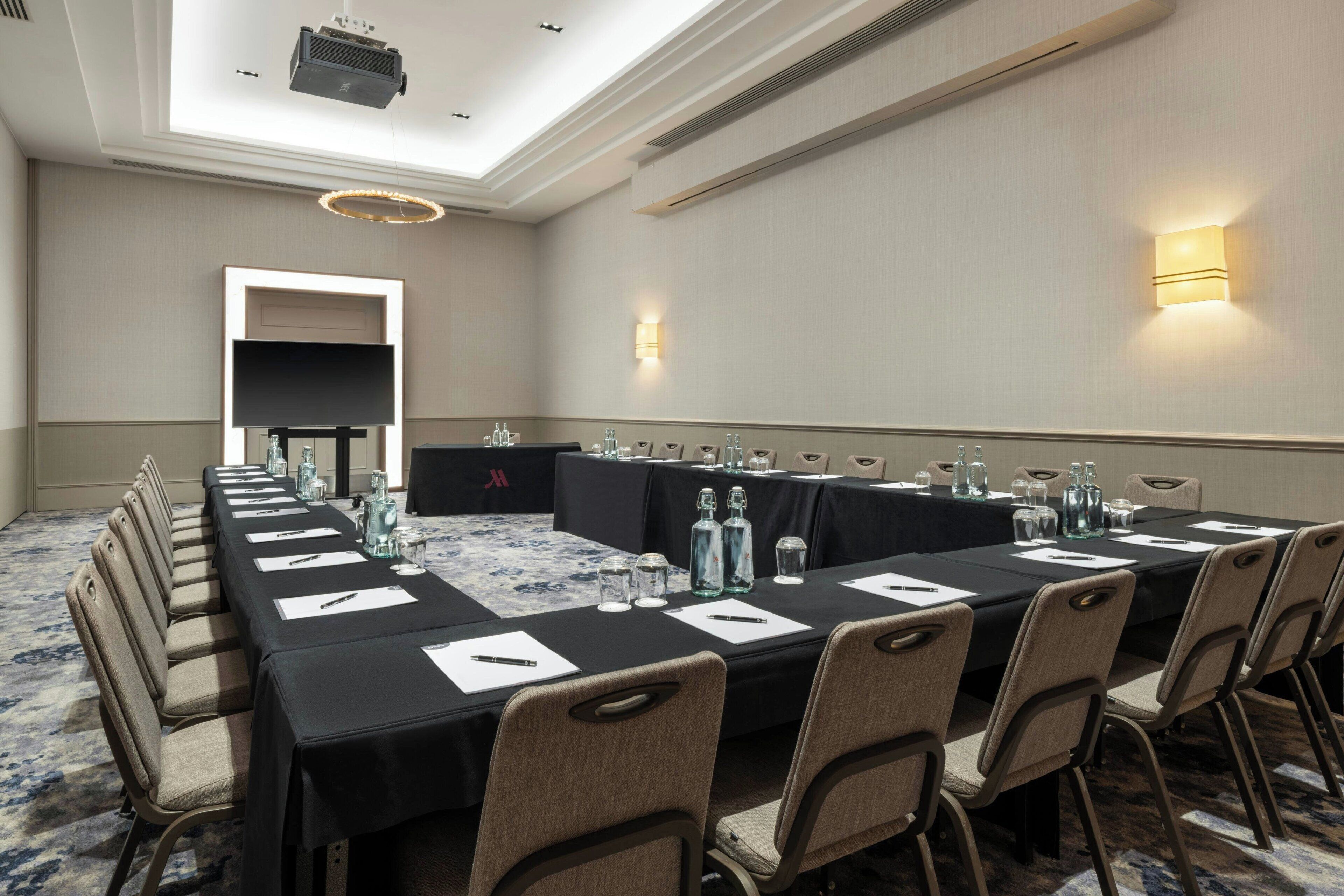 A conference room with a long table, chairs, and a projector.