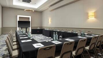A conference room with a long table, chairs, and a projector.