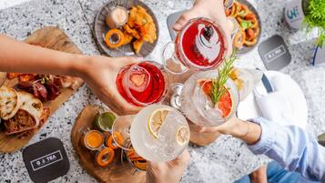 A group of people holding drinks at a table with various food items and condiments.