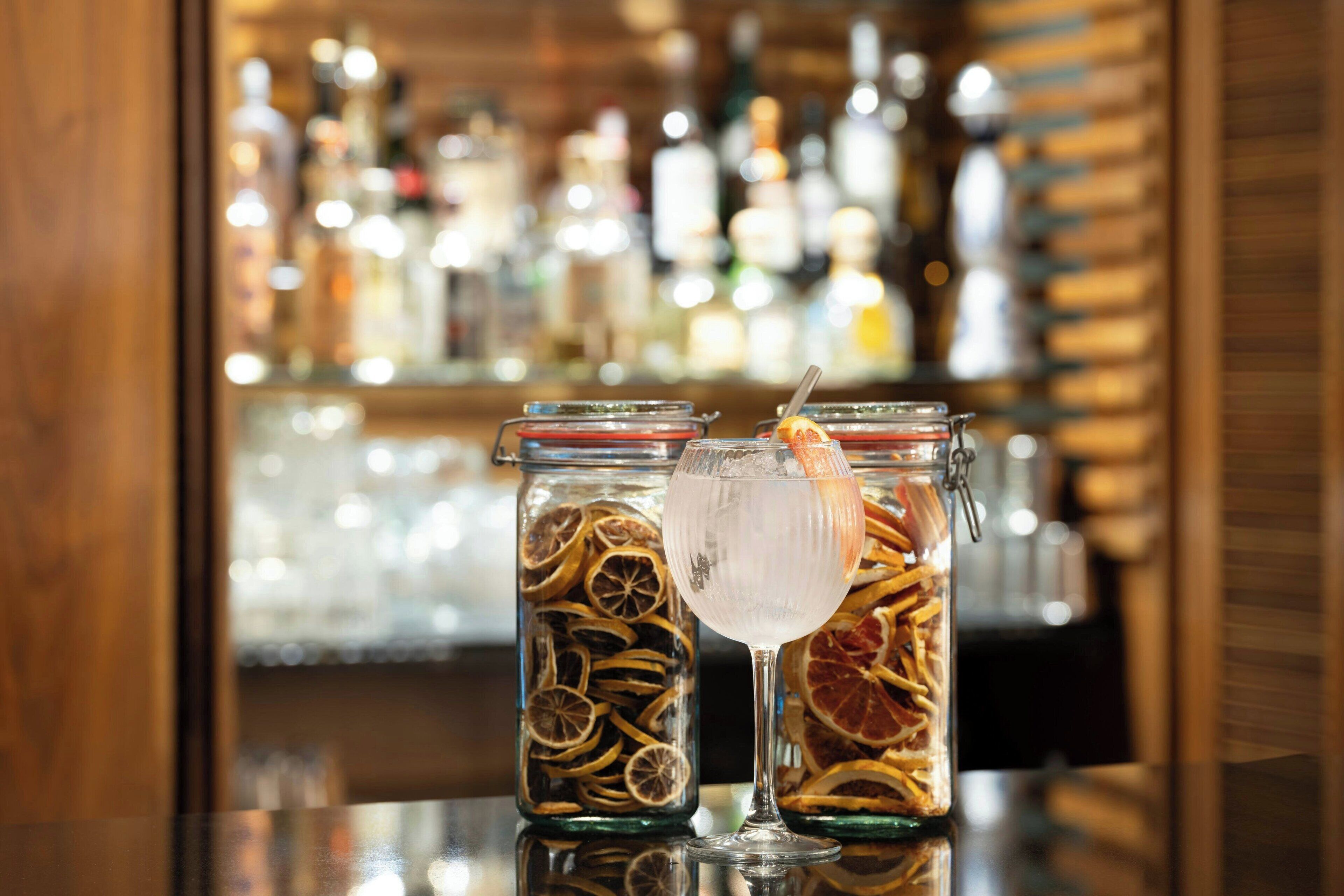 Two glass jars with dried fruits and a cocktail glass on a bar counter.