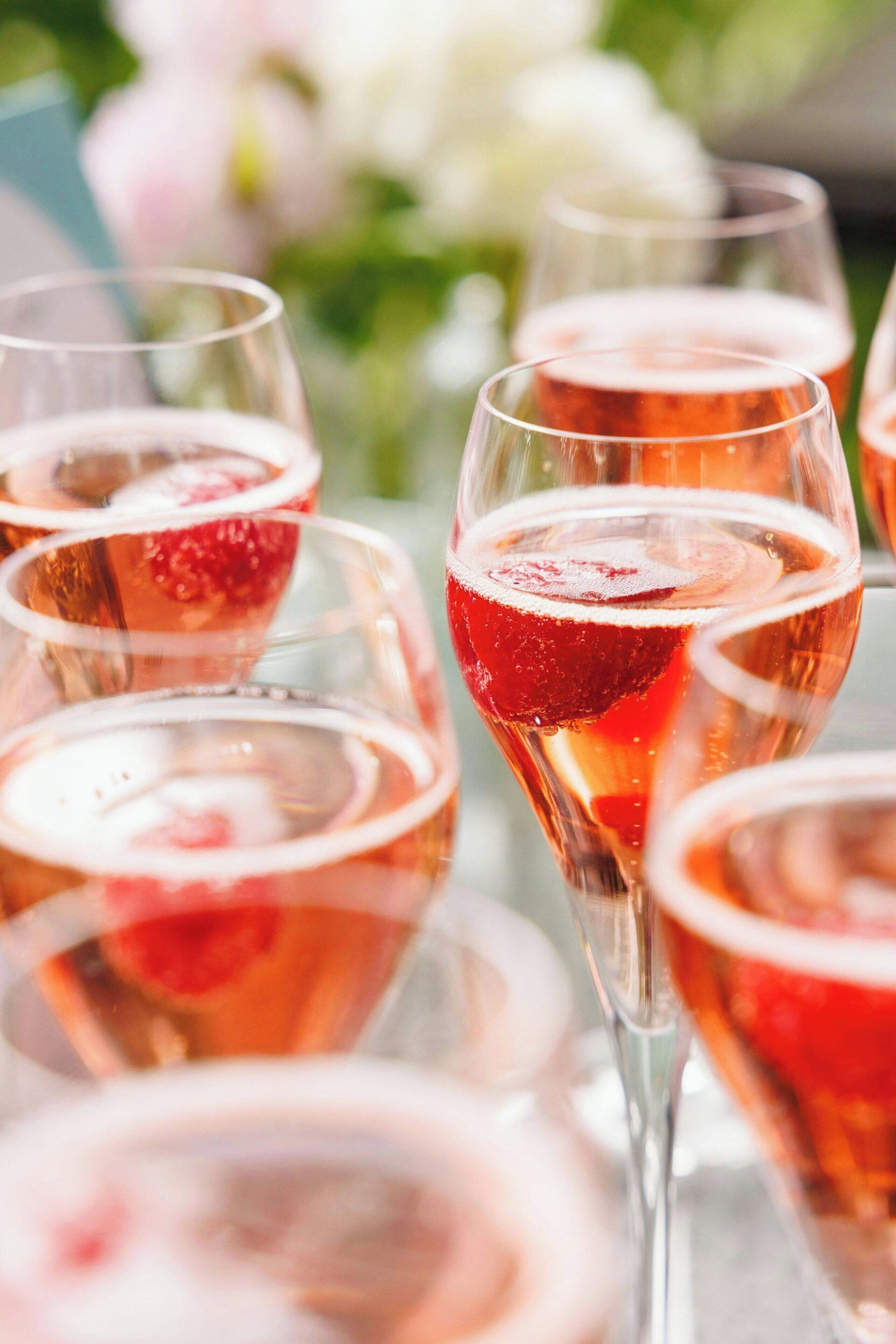 Diversos vasos amb una beguda rosa, possiblement un còctel, i una làmina de fruita al vorell.