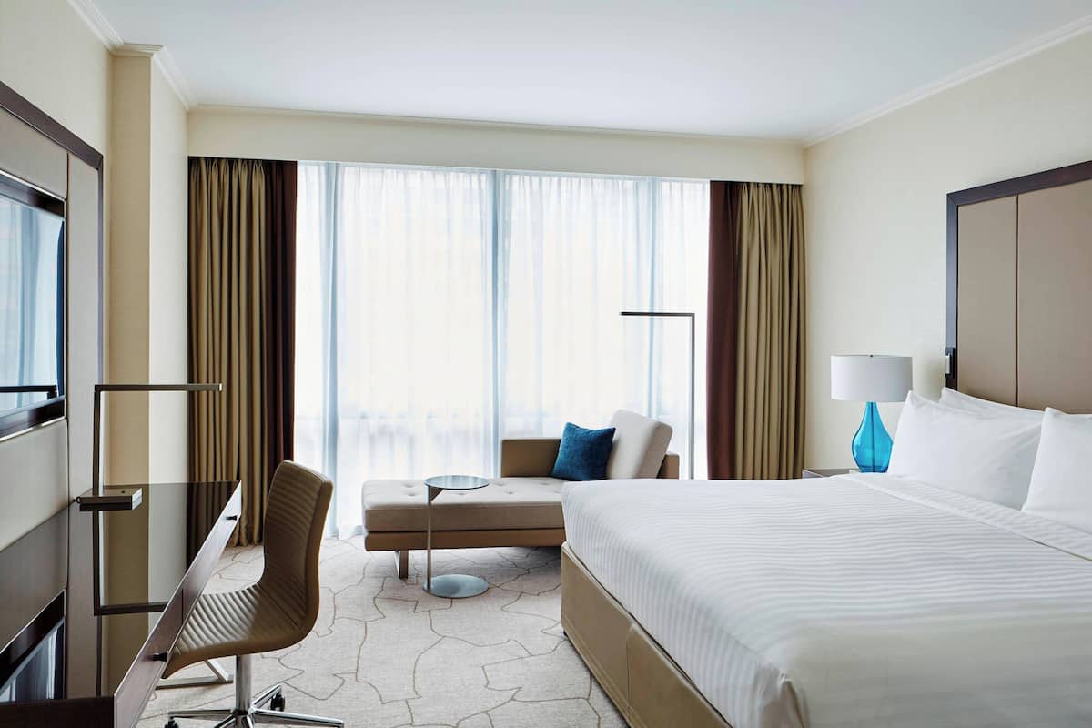 Ein Hotelzimmer mit einem großen Bett, einem Schreibtisch mit Stuhl, einer Sitzecke und einem Fernseher.