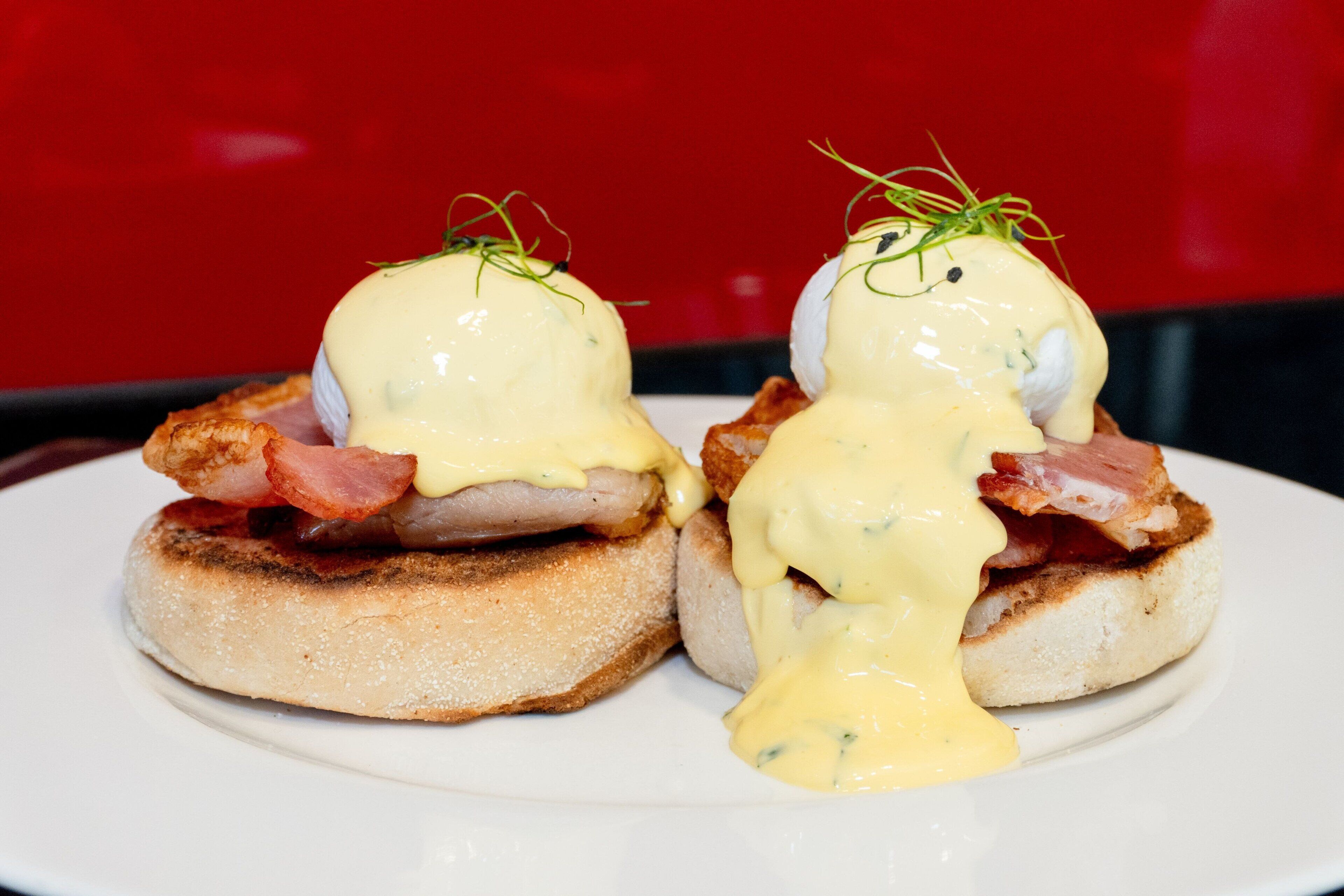 Two eggs benedict sandwiches on a white plate.