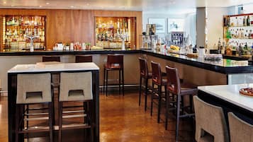 A bar area with wooden paneling, a variety of liquor bottles, and bar stools.