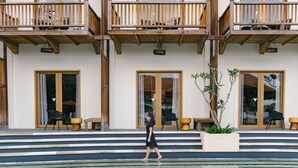 Un edificio moderno con balcones de madera, grandes puertas de vidrio y una zona de piscina.